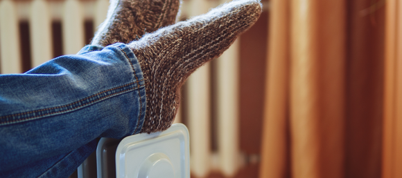 Socked feet propped up on a radiator style liquid portable heater