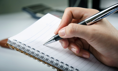 A close-up of a pen writing on a notebook.