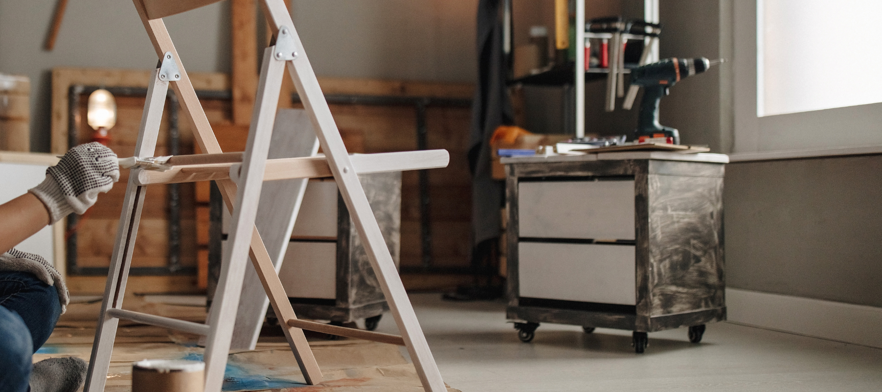 A chair being painted by a white paint brush in a garage.